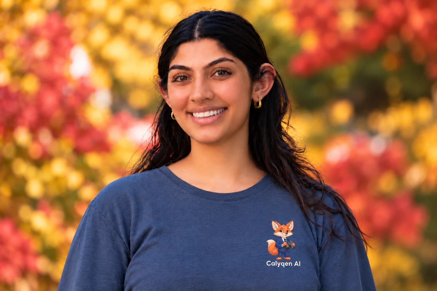 Nikita Tejwani smiling, in a navy Calyqen AI t-shirt, in front of autumn leaves.