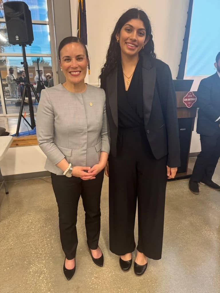 Nikita and the mayor of San Antonio stand together, smiling, in front of a podium with a City of San Antonio sign.